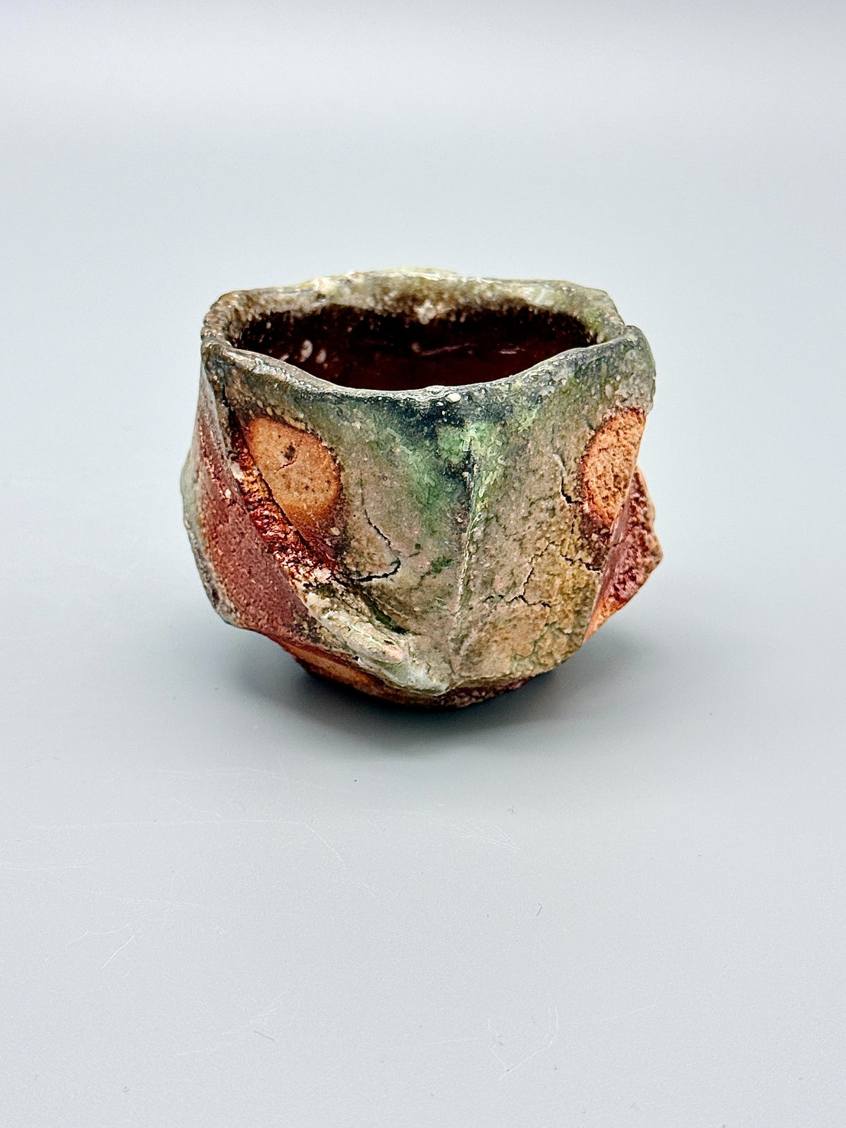 Atarashi Manabu Iga kurinuki cup, front view with green glaze, orange clay and carved planes.