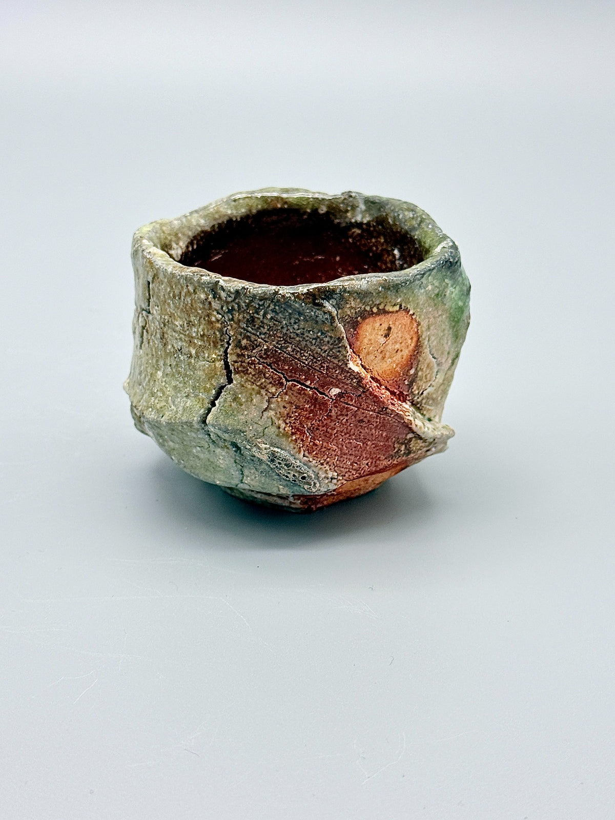 Side view of Atarashi Manabu Iga kurinuki cup, showing a diagonal carved ridge and exposed reddish clay.