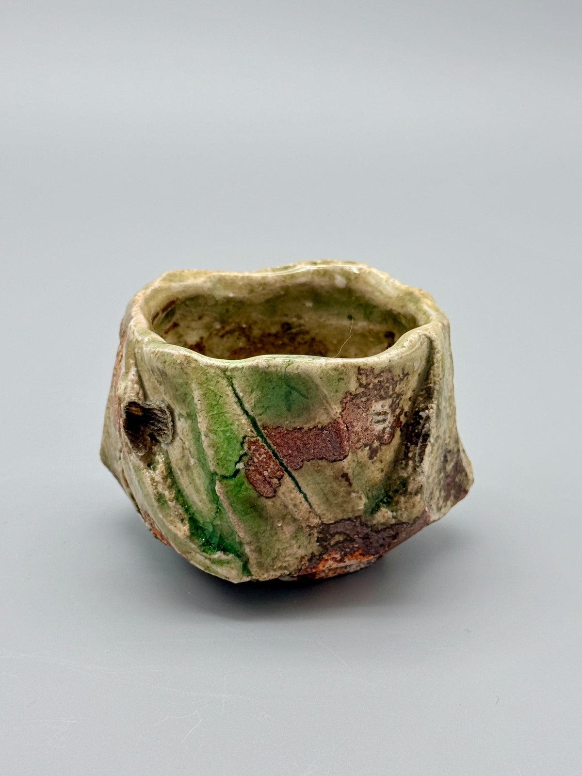Atarashi Manabu Iga cup with painterly green glaze, metallic brown clay and a shell-support mark.