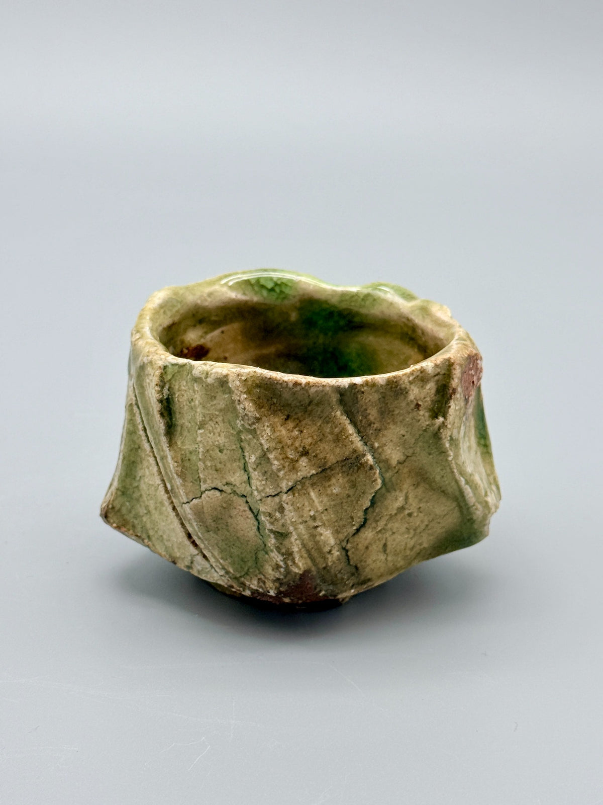 Reverse of Atarashi Manabu Iga cup with muted olive glaze, angular ridges and branching surface lines.