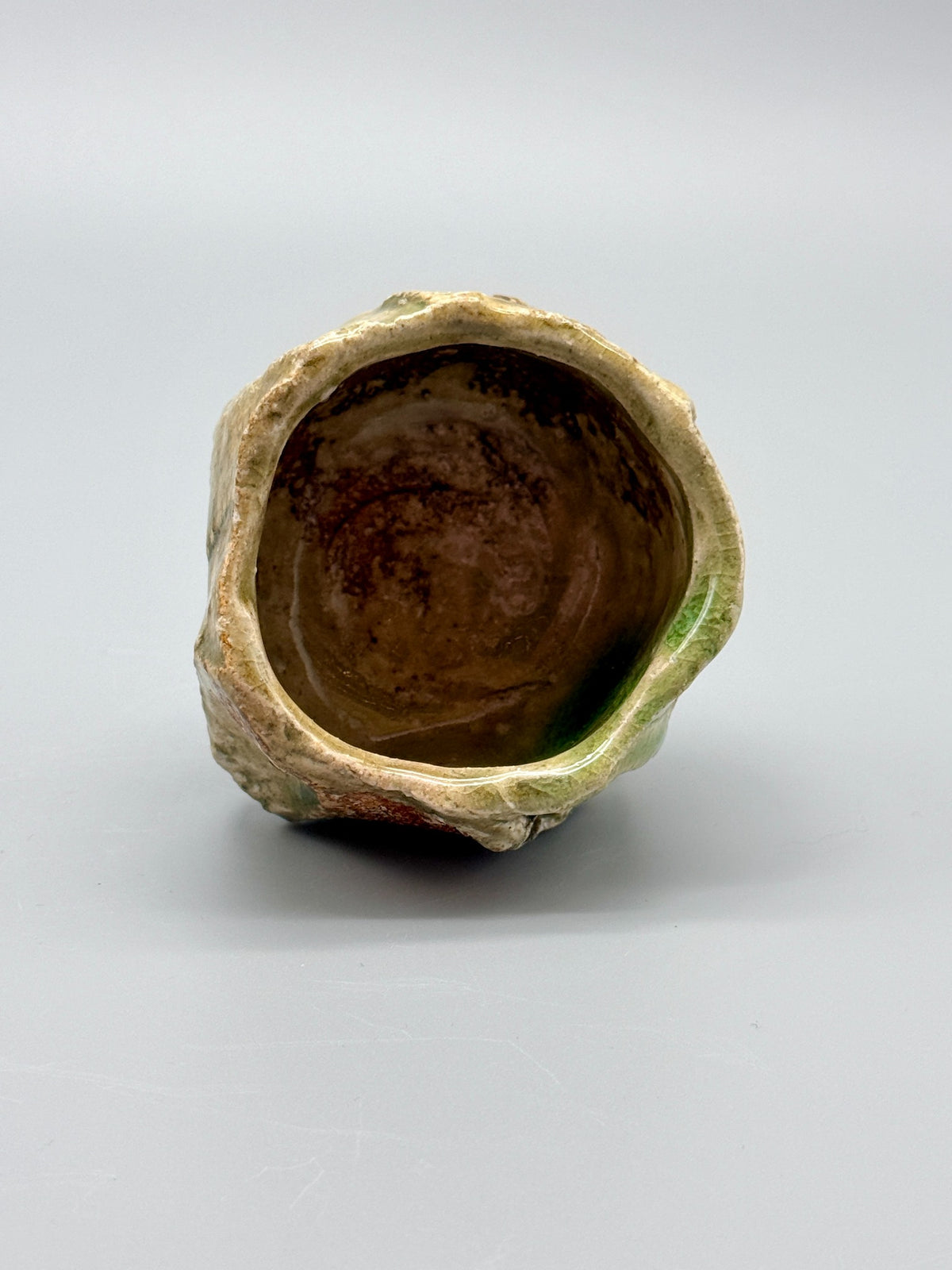 Mottled interior and uneven glazed rim of Atarashi Manabu Green Landscape Iga cup.