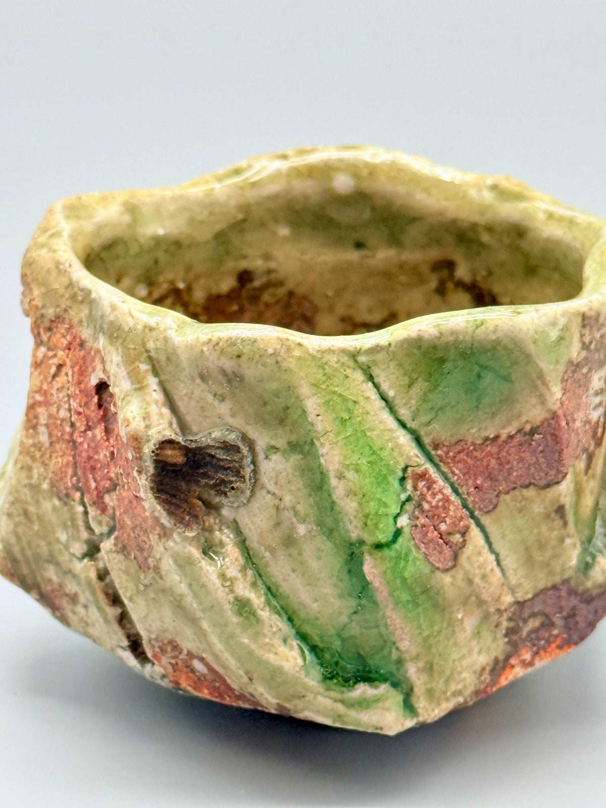 Detail of the ribbed shell-support mark and pooled green glaze on Atarashi Manabu Iga cup.