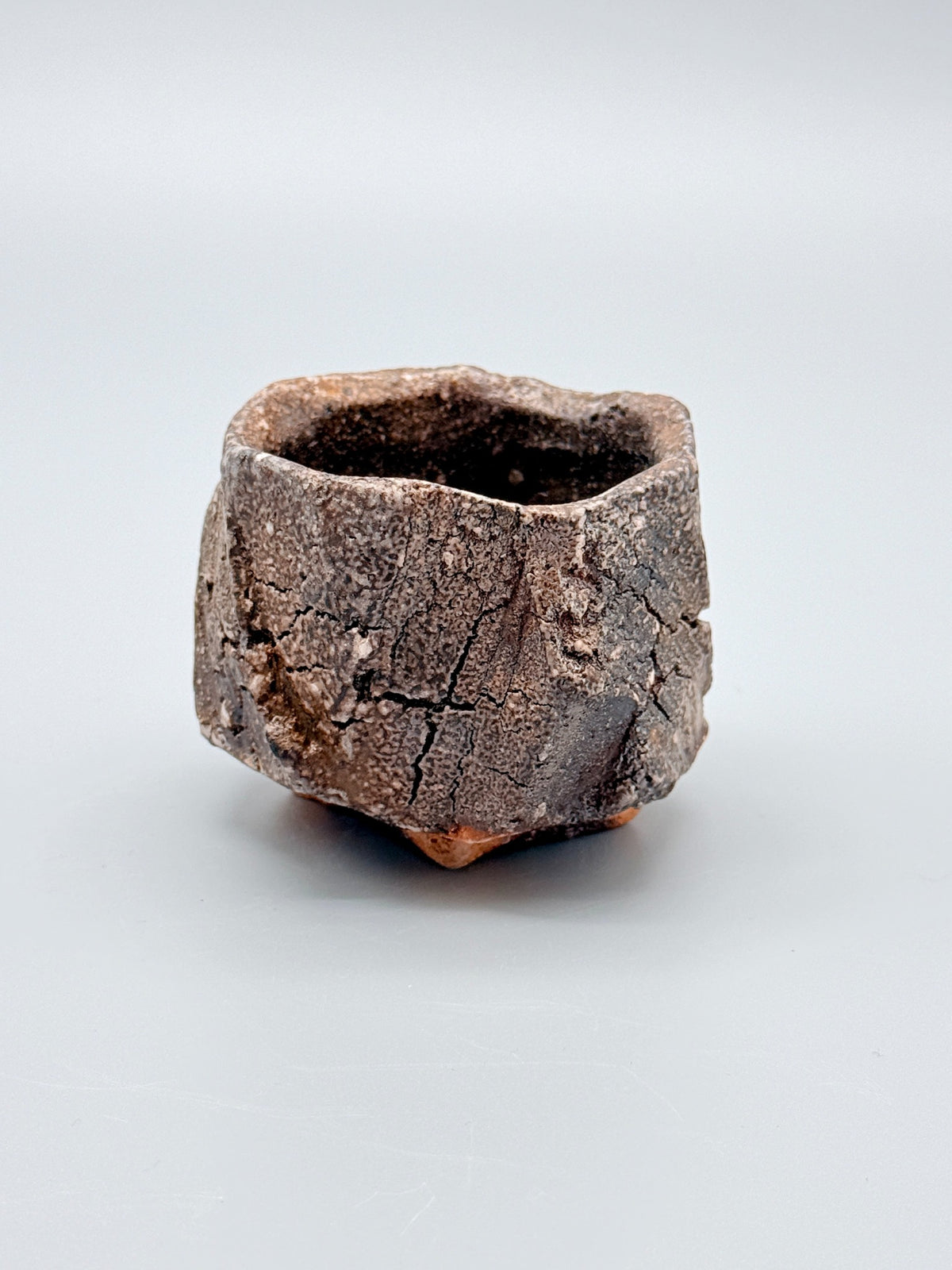 Reverse of Atarashi Manabu hikidashi black Iga cup showing granular grey-black surfaces and branching lines.