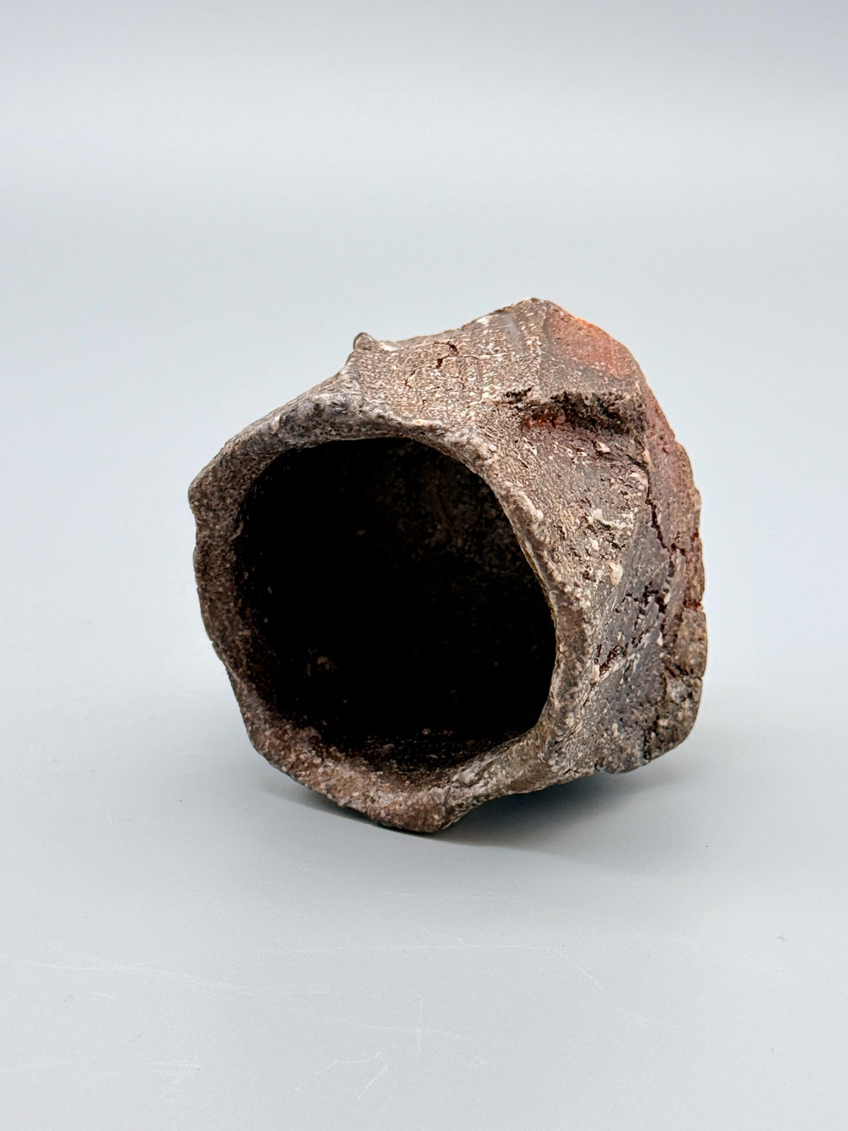 Dark interior and roughly square opening of Atarashi Manabu hikidashi black Iga kurinuki cup.