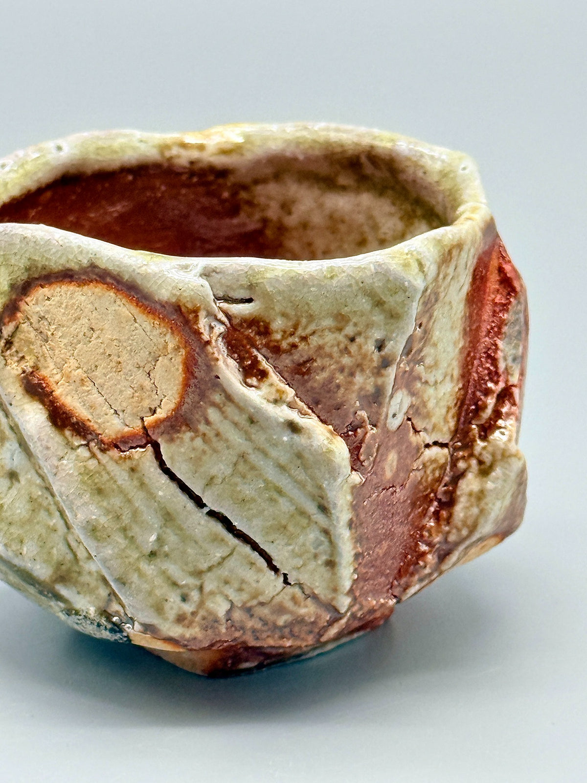 Detail of pale yellow-green glaze, granular texture and branching surface fissures on Atarashi Manabu Iga cup.